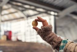 Homeless holding gold coin of cryptocurrency